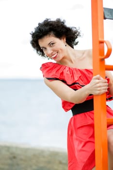 Woman in red dress climbs by orange ladder