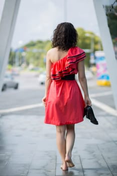 Woman in red dress walking barefoot on square