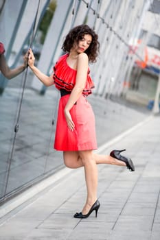 Woman in red dress next to angle wall