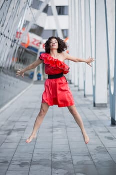 Woman in red dress jump both hands behind