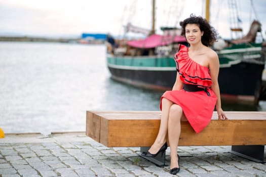 Woman in red dress posing at harbor pier