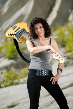Woman posing with yellow bass guitar over shoulder