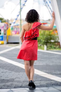 Woman in red dress moving towards fair attractions