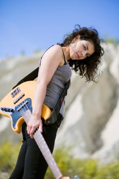 Nice looking young woman posing with yellow guitar