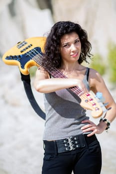Woman with guitar over shoulder on sandy background