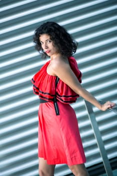 Flexible woman in red dress at striped background