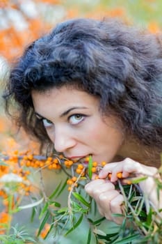 Nice looking young woman eat gooseberries from branch