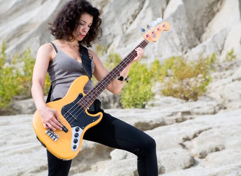 Woman on sandy background posing with yellow guitar