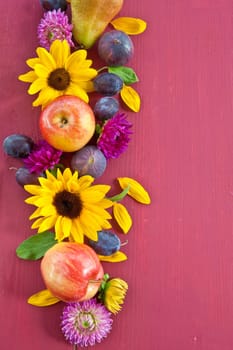 Red background with a frame of autumn fruits and flowers
