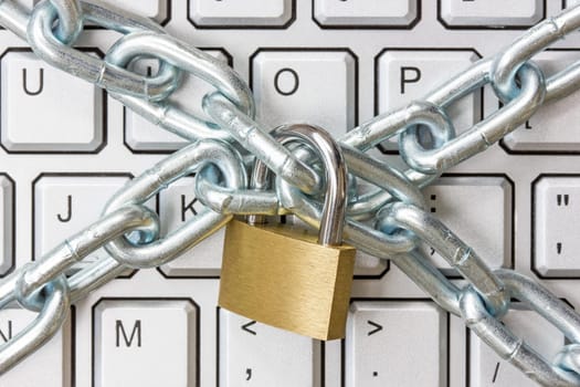 Locked chain on computer keyboard as symbol for danger in internet