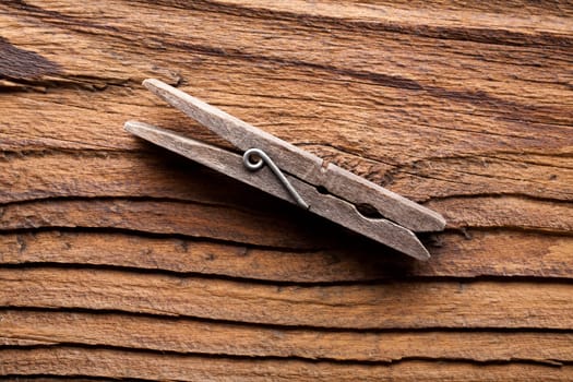 A clothes peg on a dark coarse-grained wooden background