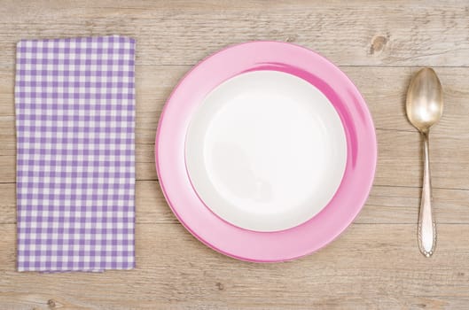 Plates,spoons and purple checkered napkin on wood