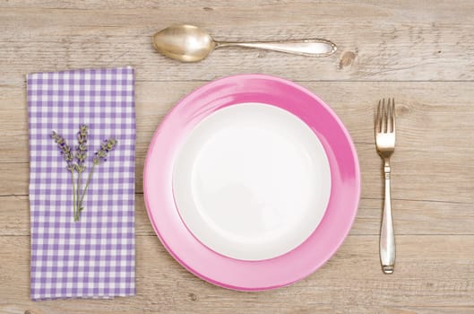 Knife,fork and plate on rustic wooden table with purple napkin