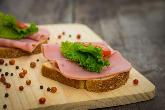Delicious ham sandwiches on wooden textured background.