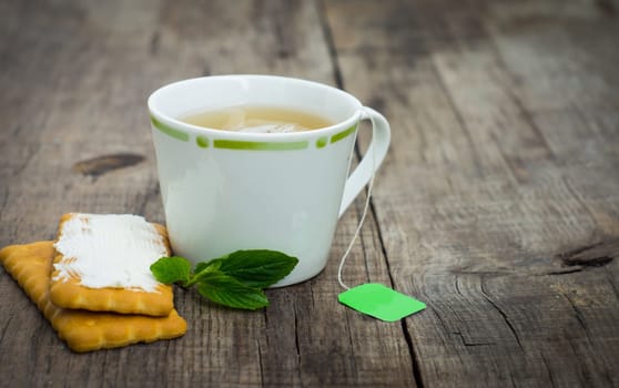 A cup of mint tea with cookies on wood background