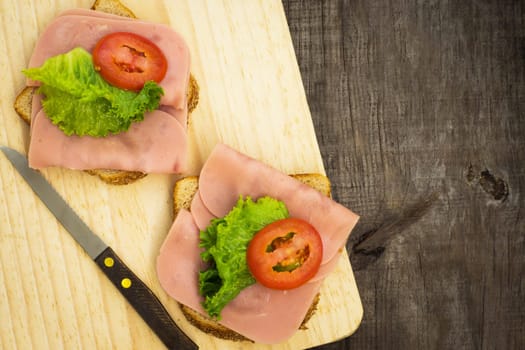 Delicious ham sandwiches on wooden textured background.