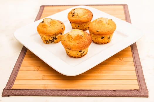 Vanilla with chocolate chips Muffins on a white plate .