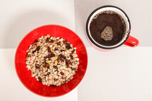 A cup of coffee and a bowl with mixed fruit Muesli.