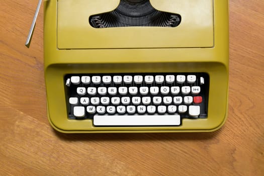 Top down view on the alphanumeric keyboard of an old retro typewriter on a wooden desk in a communication or business concept