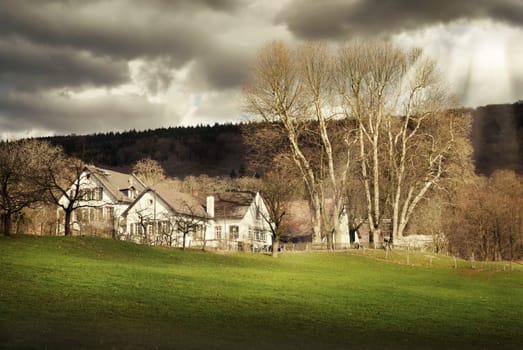 Farm on a meadow at the edge of the forest,with intense lighting mood