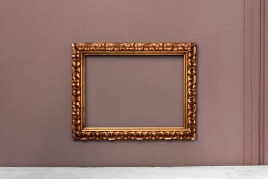 Ornate gold wooden vintage picture frame hanging on an interior wall ready for your artwork or painting in an interior decor concept