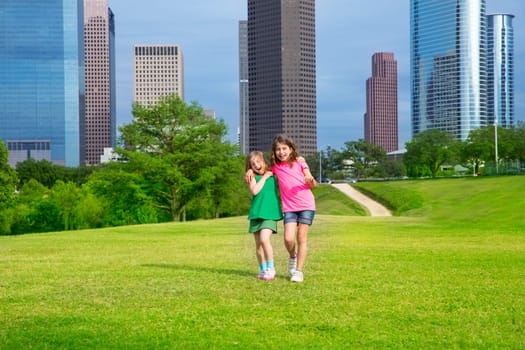 Two sister girls friends walking  in urban modern skyline on park lawn