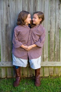 twin girls fancy dressed up pretending be siamese with his father shirt looking eachother
