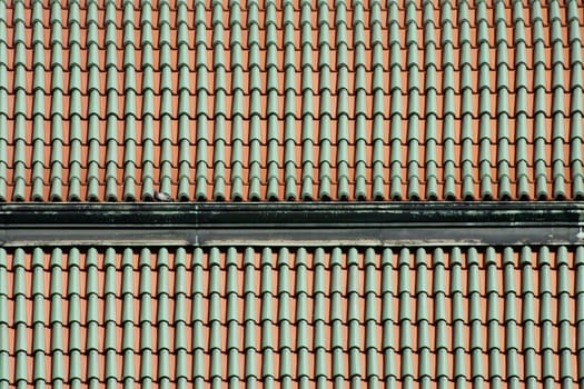 The photograph of a tiled roof on which a pigeon walks.
