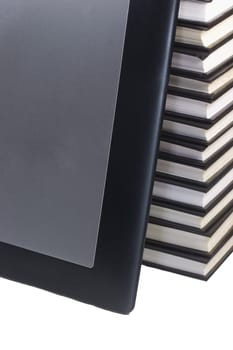 Tablet leaning on books. White background.