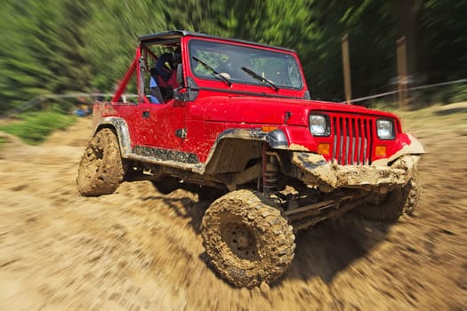 Red off-road car in difficult terrain. Blurred background. All potential trademarks are removed.