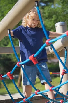 Young blond boy is playing at monkey bars. Vertically.