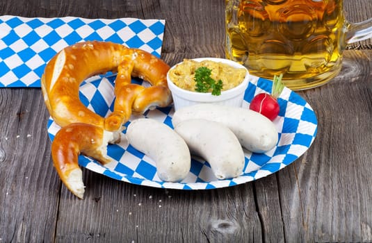Typical Bavarian Oktoberfest meal with veal sausage,mustard,pretzels and a cool beer on a blue and white paper plate