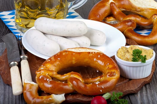 Typical Bavarian Oktoberfest meal with veal sausage,mustard,pretzels and a cool beer on a rustic wooden table