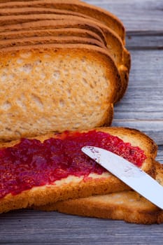 Pain Grille - French toast spread with jelly and a knife on a wooden table