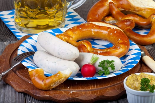 Typical Bavarian Oktoberfest meal with veal sausage,mustard,pretzels and a cold beer on a rustic Holzti