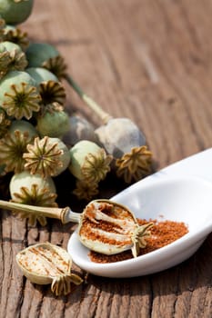 Poppy seed capsule,poppy seeds in a small bowl stand on an old rustic wooden table