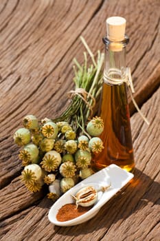 Poppy seed capsule,poppy seeds and a bottle of poppy seed oil stand on an old rustic wooden table