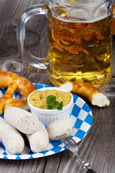 Typical Bavarian Oktoberfest meal with veal sausage,mustard,pretzels and a cool beer on a rustic wooden table