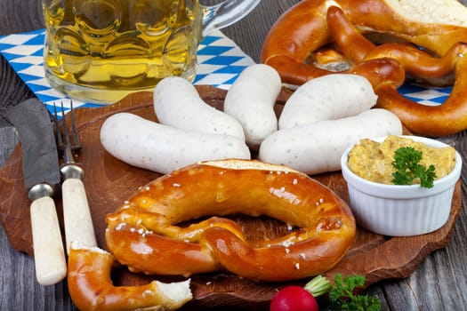 Typical Bavarian Oktoberfest meal with veal sausage,mustard,pretzels and a cold beer on a rustic Holzti