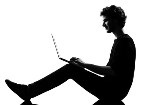 young man silhouette silhouette sitting computing computer laptop in studio isolated on white background