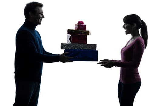 one caucasian couple woman man offering christmas  gifts in silhouette studio isolated on white background