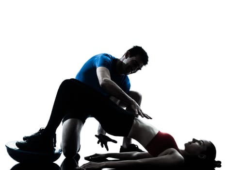 personal trainer man coach and woman exercising abdominals push ups on bosu silhouette  studio isolated on white background