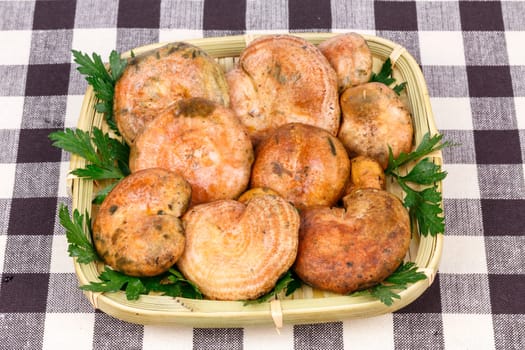 mushrooms, rovellons type, presented in little basket with parsley on checkered tablecloth