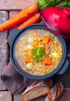 Overhead view of a thick wholesome vegetarian vegetable and lentil stew served with sliced bread on bricks