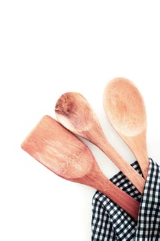 Three different types of wooden kitchen utensils in a checkered kitchen towel , on white background