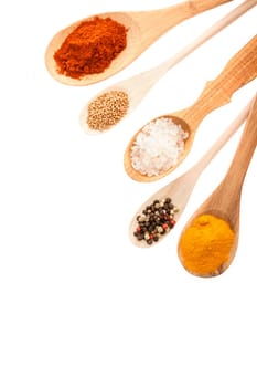 Wooden ladles of assorted sizes and shapes filled with colourful culinary spices and condiments, overhead view with copyspace