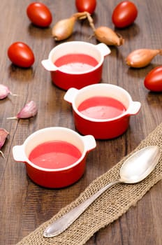 Red tomato soup soup in soup cups on a table with brown wood