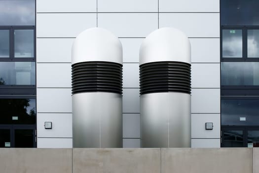 The photograph of two ventilation hoods in front of a modern building.