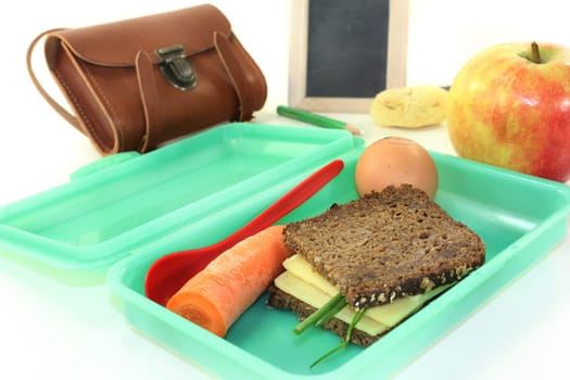 a bread box with a sandwich and a carrot and an apple