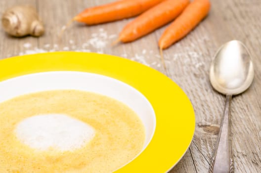 Carrot soup with foam of coconut milk on a wooden table